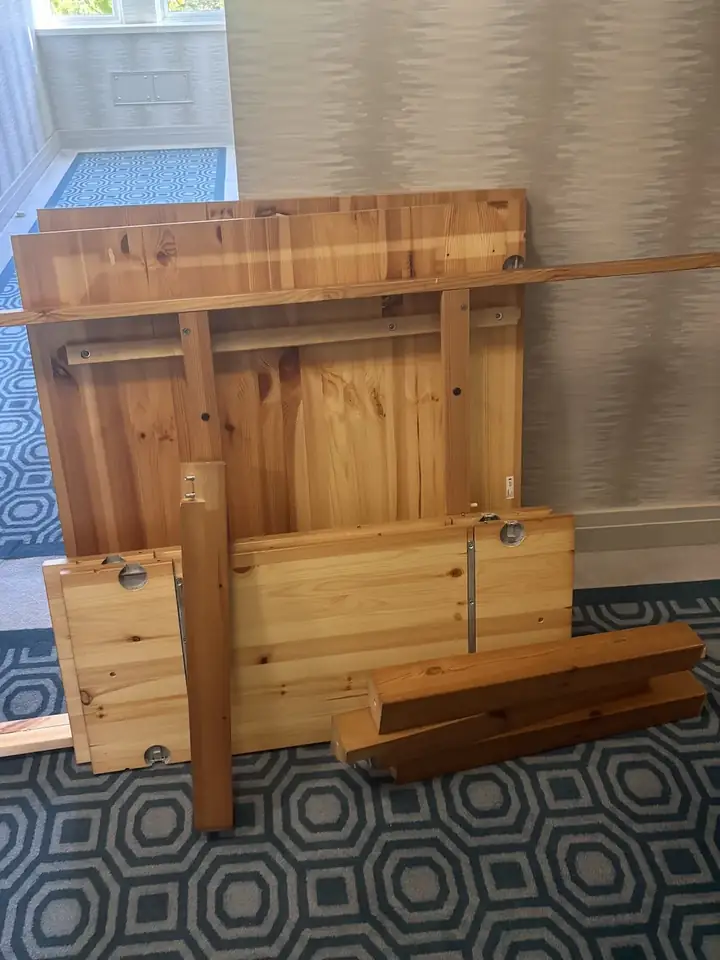Dining table removal off Sloane Street SW1X: solid pine table dismantled into its top, leaves, legs and rails, stacked in the building corridor ready for the lift