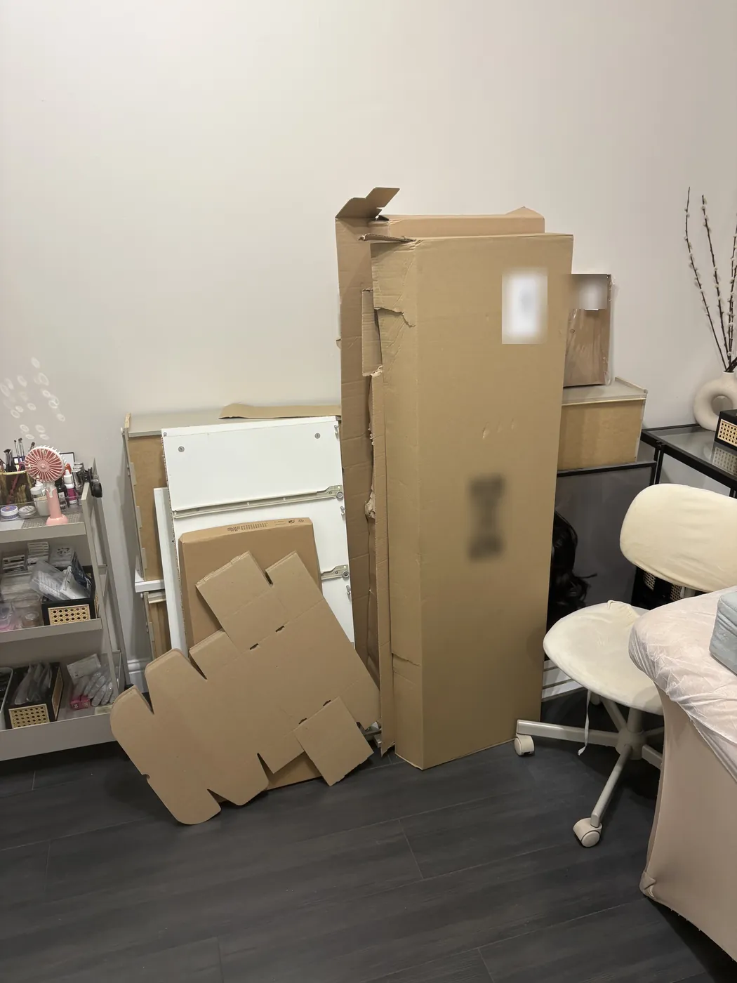 Flat-pack furniture boxes, a white panel and cardboard packaging stacked in the corner of a treatment room on Cleveland Street, Fitzrovia, before collection.