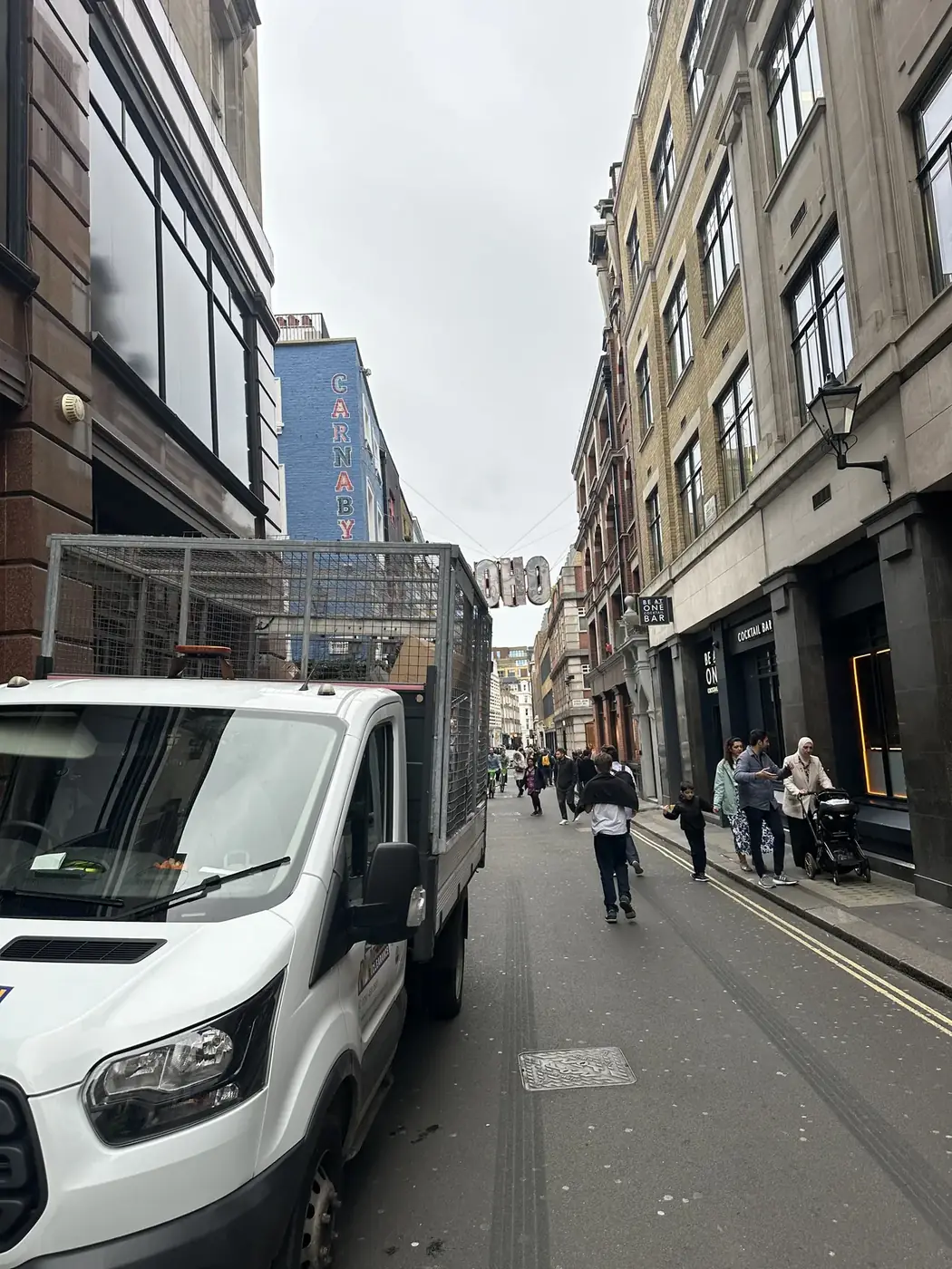 Waste collection vehicle on a busy Soho street near the Carnaby shopping district.